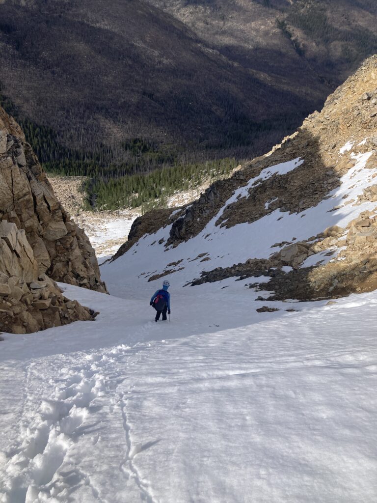 Carolyn plung steps down a steep snow chute in the Pasayten Wilderness