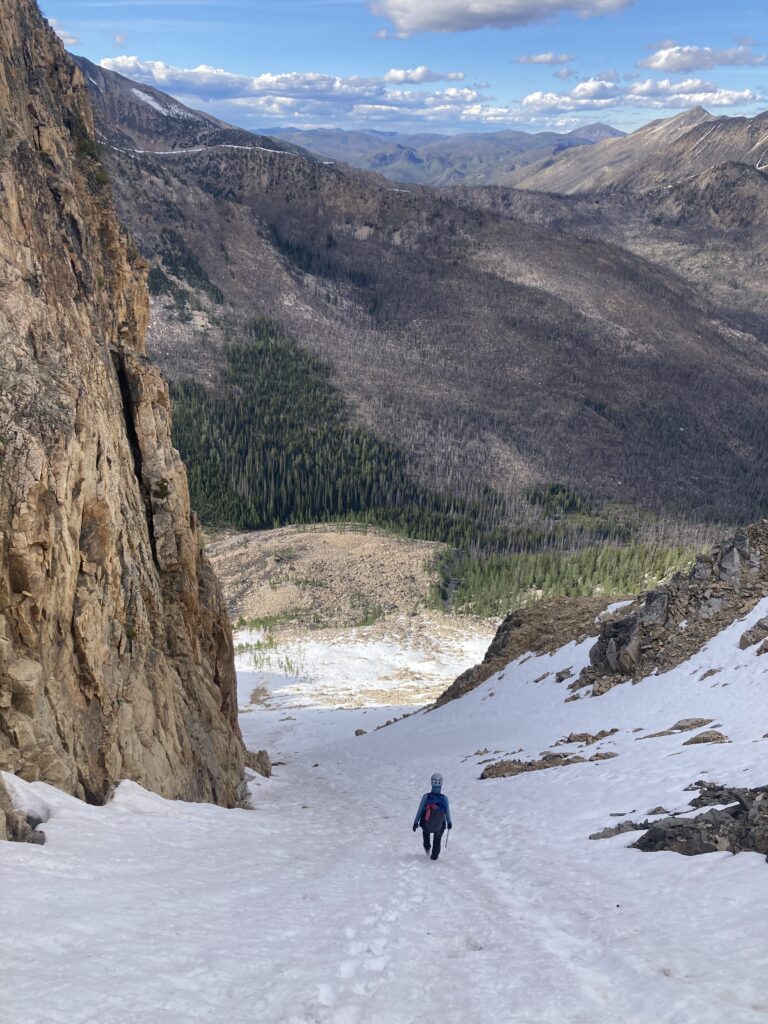 Carolyn hiking down steep snow in the Pasayten Wilderness in WA state