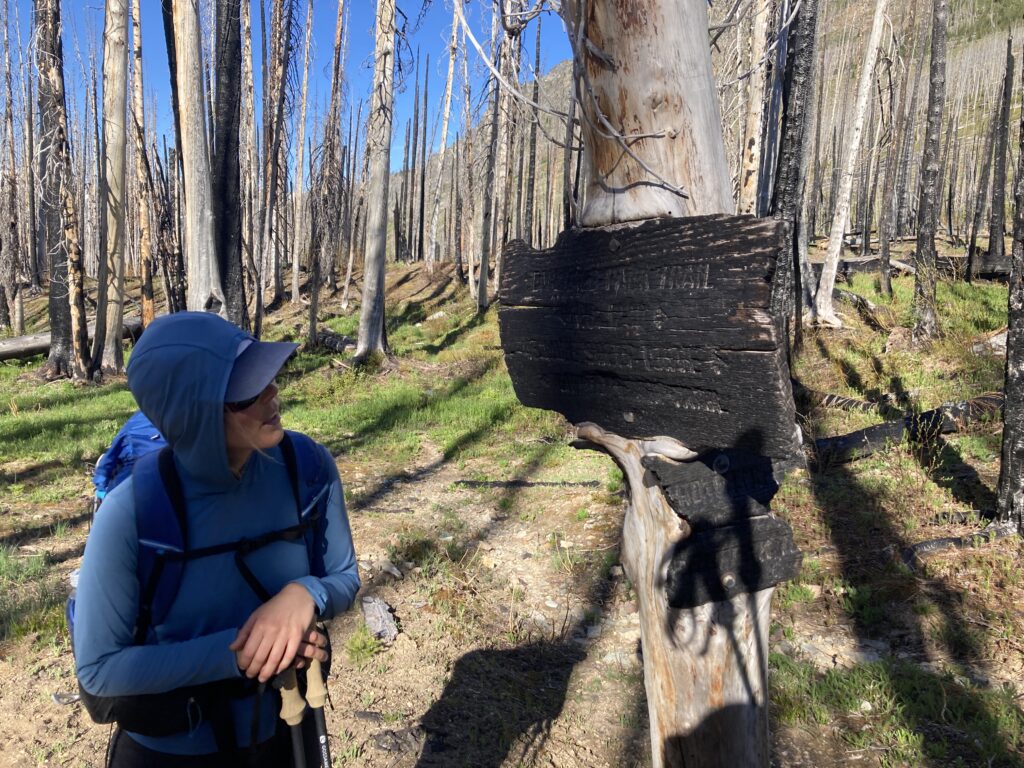 Carolyn looking at a burned up trail sign in the Glacier Peak Wilderness