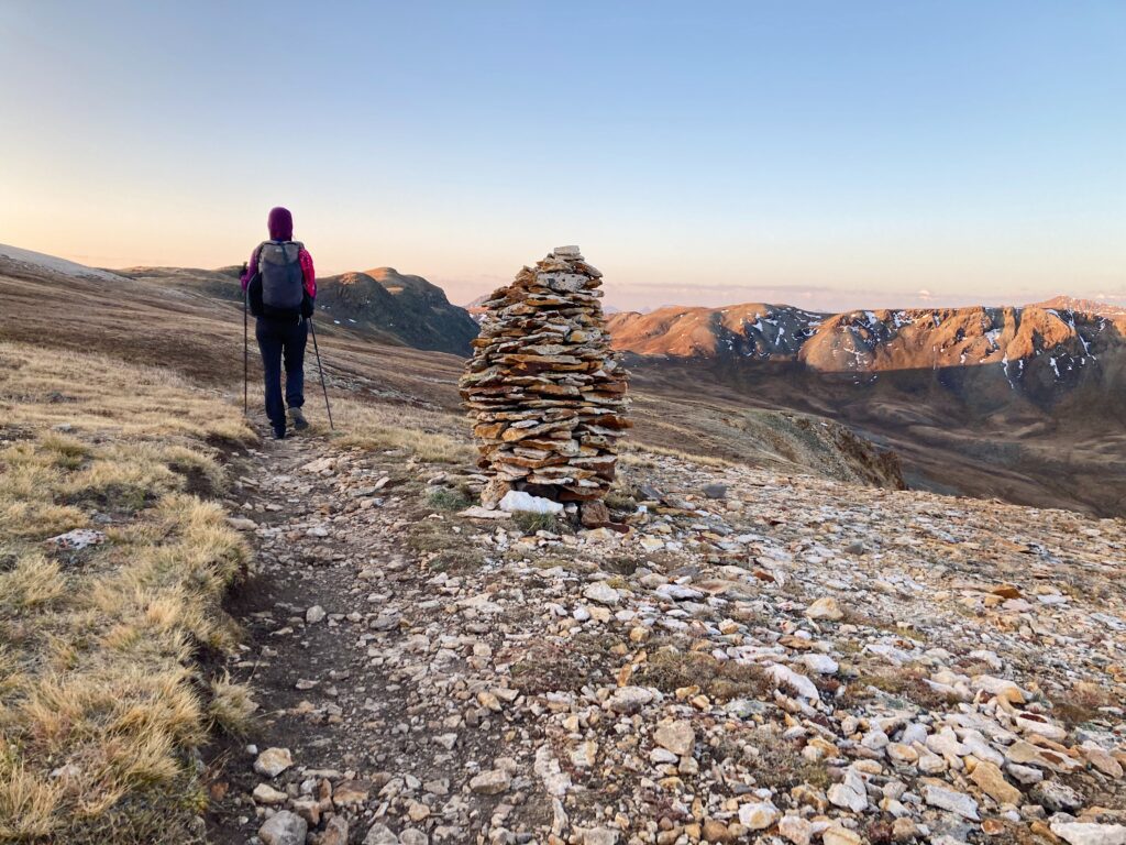 Carolyn walking by a larg cairn on the San Juans section of the Colorado Trail