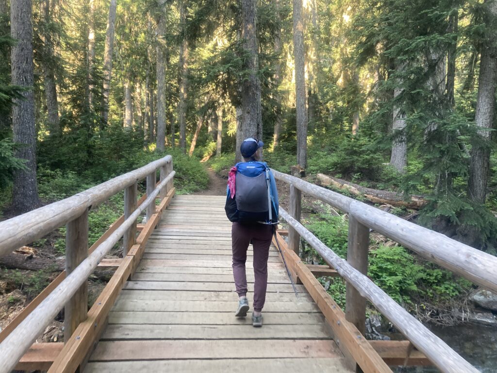 Carolyn walking across a bridge on the Pacific Crest Trail in the North Cascades of Washington