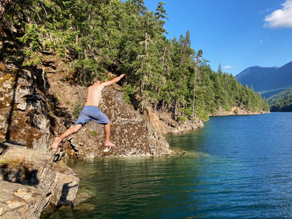 Jeff jumping off a cliff into Ross Lake on the Cougar Traverse