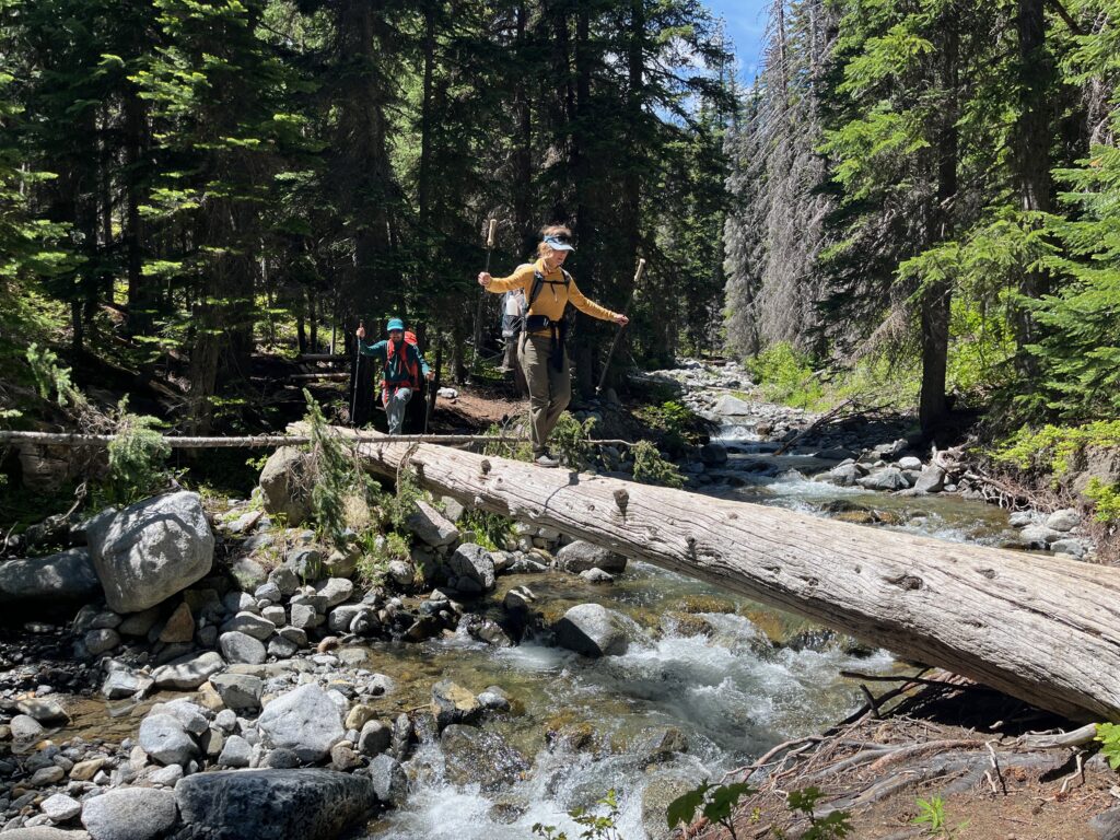 Carolyn walking across Ingalls Creek on a log in Alpine Lake Wildernss headed to climb Sherpa Peak