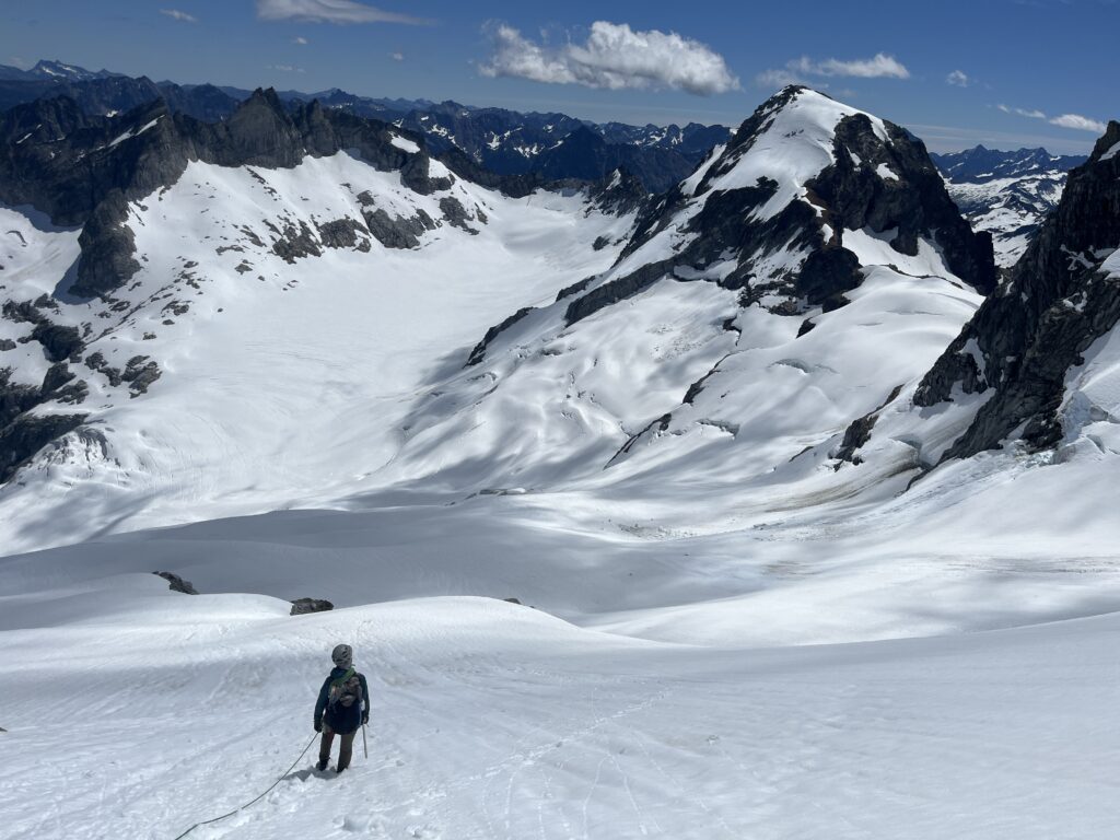 View of Carolyn walking down the Chikamin Glacier towards Sinister Peak in Glacier Peak Wilderness