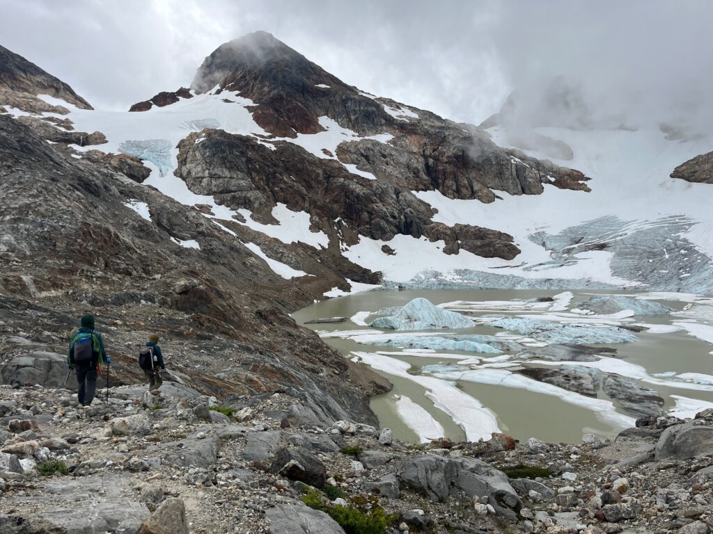 Hikers walking along the east side of Colonial Lake in the North Cascades while on the Isolation Traverse