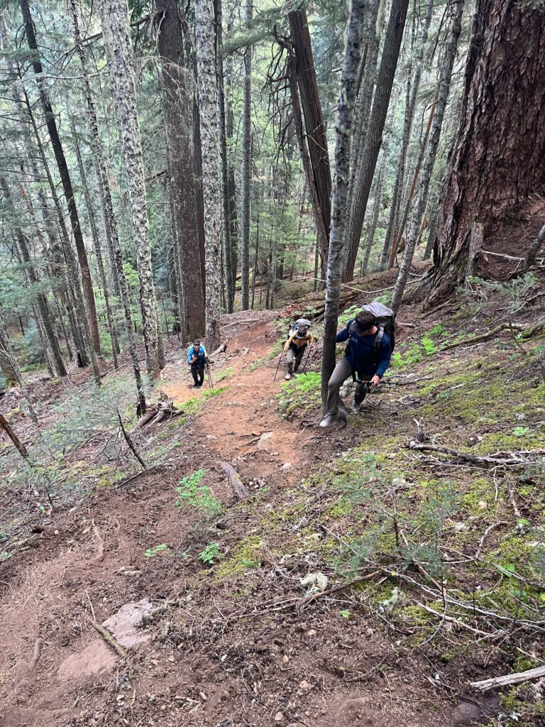 Backpackers hike on a steep trail along the Isolation Traverse in the North Cascades