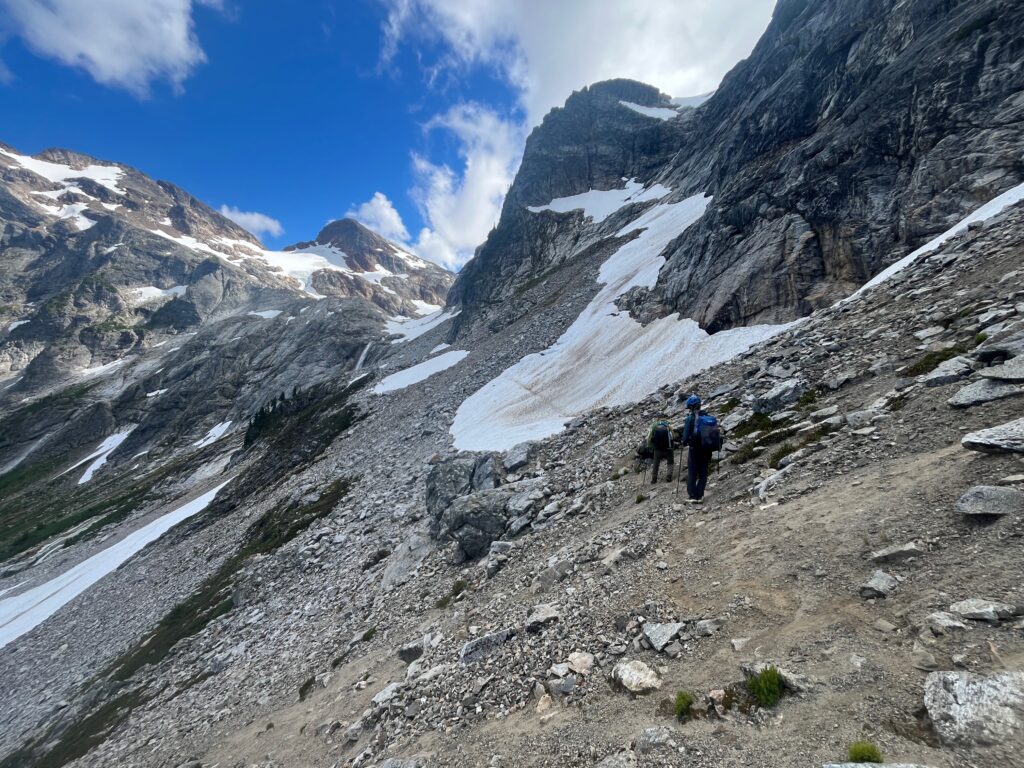 Hiker crossing a slope under Pyramid Peak along the Isolation Traverse in the North Cascades