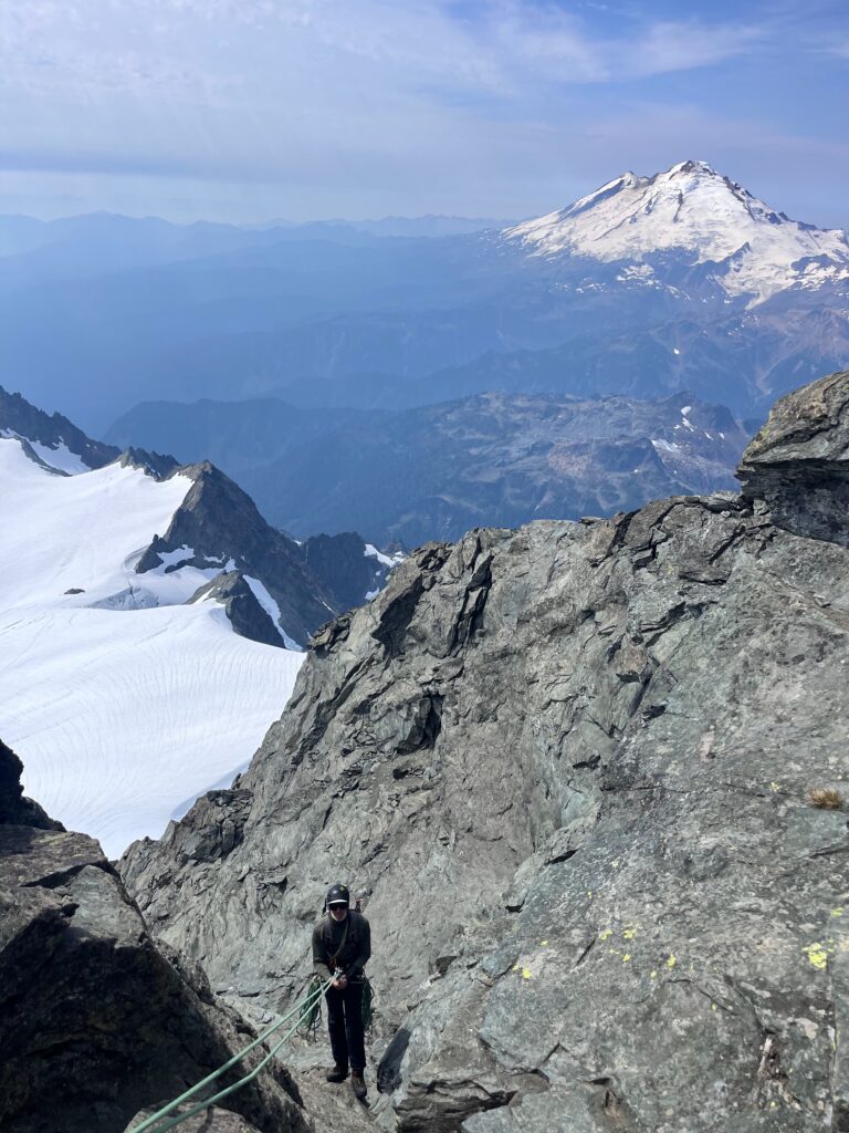 Jeff rappelling off of Mount Shuksan in North Cascades National Park with Mount Baker in the background